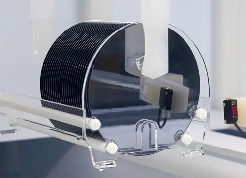 A highly detailed image of a circular Nexperia silicon wafer, featuring intricate patterns of microchips (dies) covering its surface.